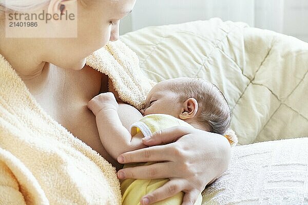 Baby eating breast milk. Caucasian blonde young mother breastfeeding her baby horizontal photo. Concept of lactation