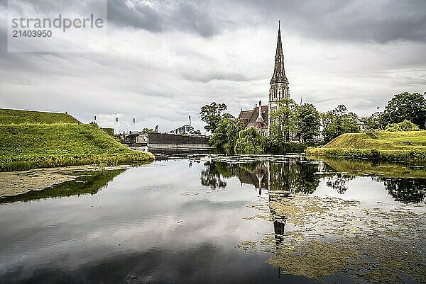 Church reflected on water pond in Churchill Park in Copenhagen a cloudy day of summer near sunset