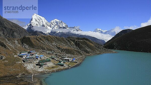 Lodges in Gokyo  turquoise lake Dudh Pokhari and snow covered mountain Cholatse  Nepal  Asia