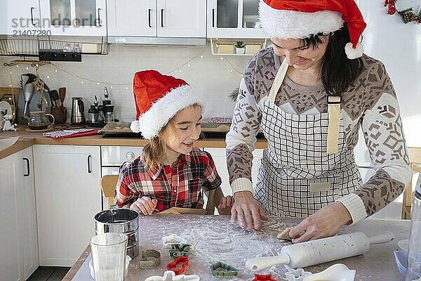 Mom and daughter in the white kitchen are preparing cookies for Christmas and new year. Family day  preparation for the holiday  learn to cook delicious pastries  cut shapes out of dough with molds