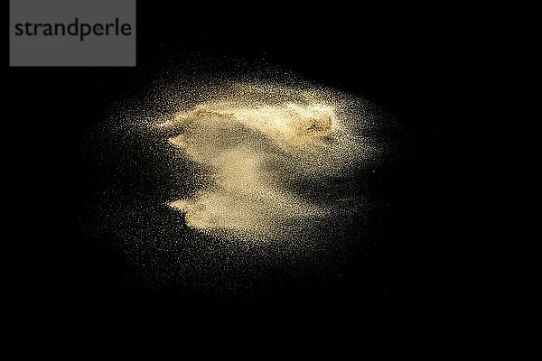 Golden sand explosion isolated on black background. Abstract sand cloud. Golden colored sand splash against dark background. Yellow sand fly wave in the air