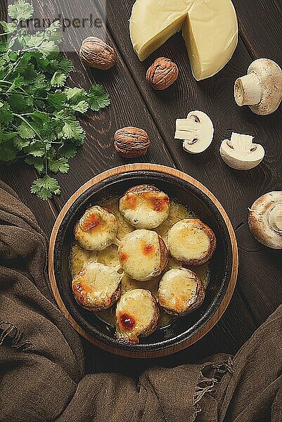 Traditional Georgian dish  appetizer  stuffed mushrooms  Sulguni cheese  baked in a Ketzi clay pan  on a wooden table  close-up  no people