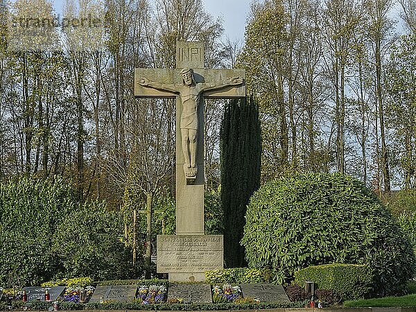 Large stone cross with statue of Christ surrounded by greenery in a cemetery  borken  münsterland  germany