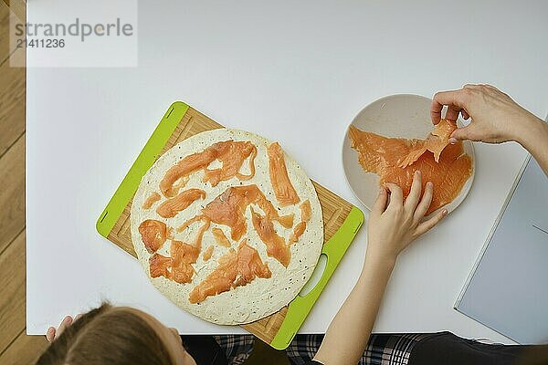 Top view of preparing flatbread with cream cheese and smoked salmon pieces