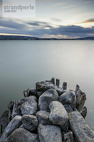 Stone pier in a calm lake in the evening light  far horizon and clouds in the sky  harbour  Allensbach  Lake Constance  Baden-Württemberg  Germany  Europe