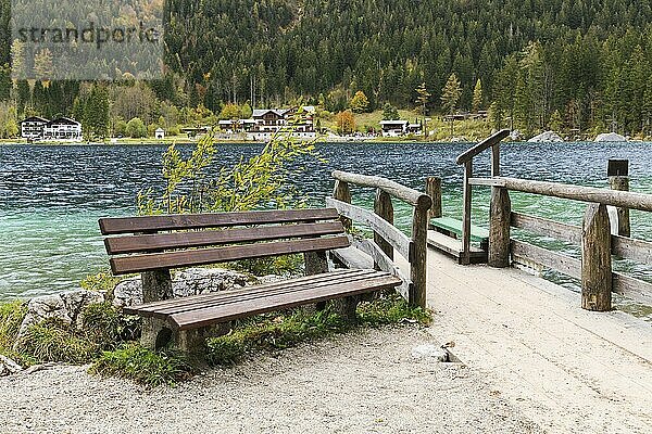 Boat landing stage with bench at Hintersee in Bavaria. Ramsau near Berchtesgaden. Hotels in the background. Jetty with park bench at the shore of the mountain lake Hintersee in Bavaria  Germany. With hotels on the far side of the lake