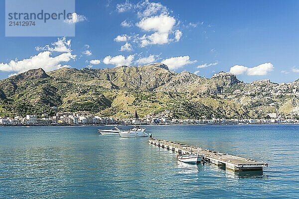 Wooden pier and some boats in beautiful bay with mountains in the background on the island Sicily in Italy