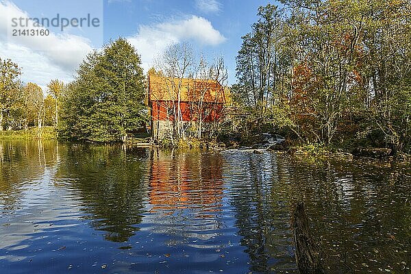 Old mill by a lake in an autumn landscape