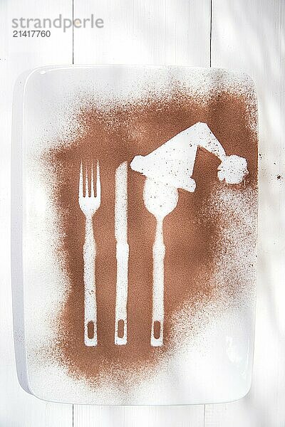 Representation of the Christmas holiday with cutlery on the plate and a dusting of cocoa