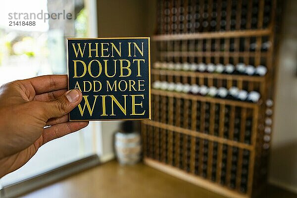 When in doubt add more wine  hand holding quote sign selective focus view against wine tasting room interior wines shop bottles on shelves background