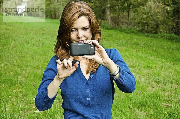 Young woman taking a photo with her smartphone in the park