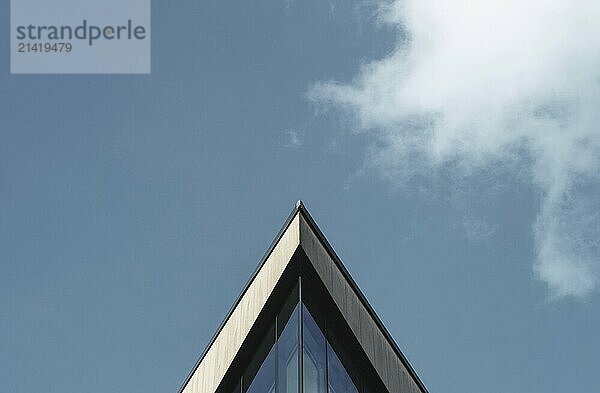 Abstract Architectural Image Of A Triangular Building Against A Blue Sky WIth Clouds And Copy Space