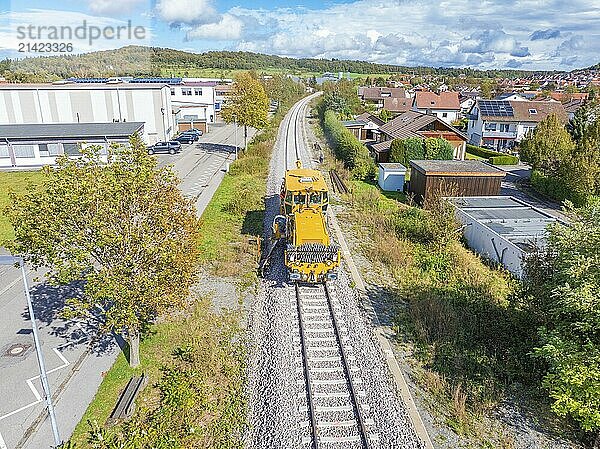 Yellow vehicle on railway tracks in the countryside  area with houses and industrial buildings  tamping machine  Hermann Hessebahn  Althengstett  Black Forest  Germany  Europe