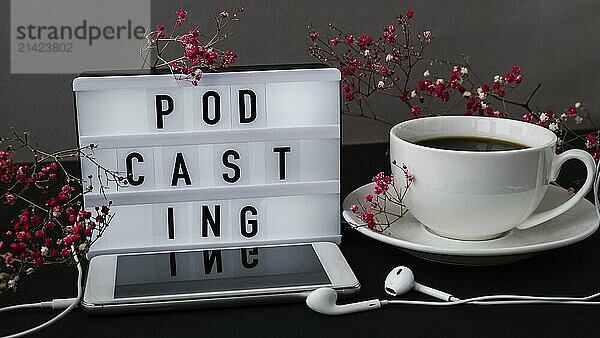 Podcasting lettering. Headphones mobile phone. Dry pink flowers decoration. Workplace. Black coffee. Podcaster  podcast Audiobooks