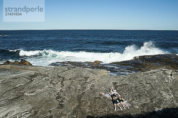 24.09.2019  Sydney  New South Wales  Australia  A group of girls sunbathing on the rocks at Tom Caddy Point near Clovelly Beach  Oceania