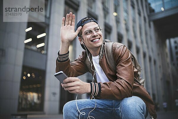 Man Sitting Listening Music Earphones Concept. Cheerful young guy listening the music