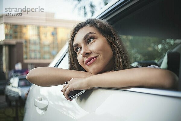 Portrait of cute smiling girl sit in the car and look at the street