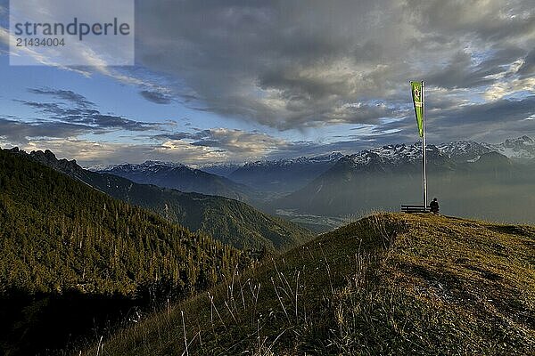 Sitting woman enjoying a dreamlike evening mood in the mountains  view to the Rätikon  flag of the Austrian Alpine Club  Frassenhütte  Vorarlberg  Austria  Europe