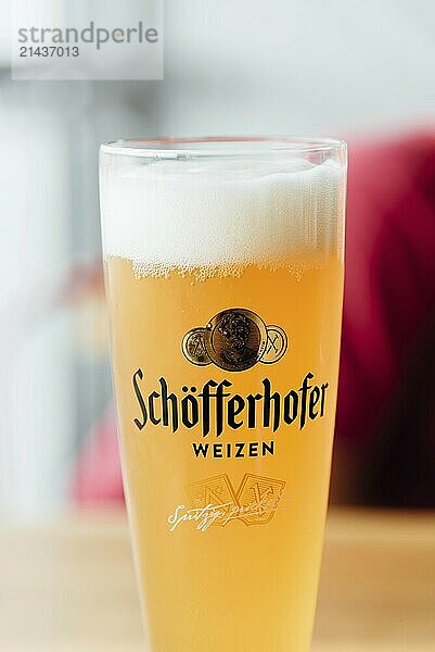 Hamburg  Germany  August 7  2019: Glowing weiss glass of Schofferhofer Beer in bar. Bokeh blurred background  Europe