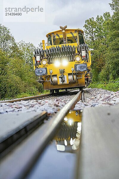 Yellow railway vehicle on tracks from a low perspective  trees in the background  tamping machine  Hermann Hessebahn  Calw  Black Forest  Germany  Europe