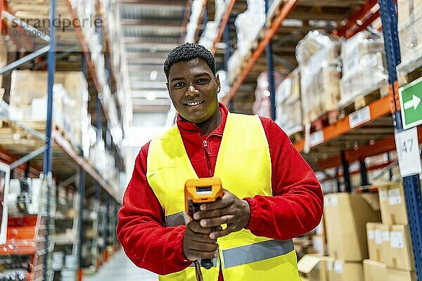 Frontal view of a latin man with modern scan machine in a storage warehouse