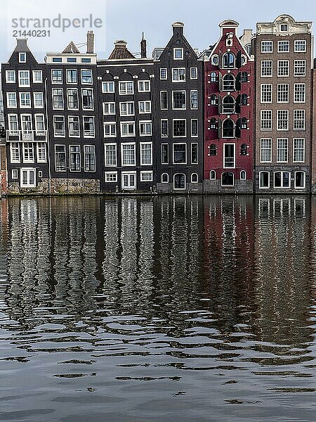 Canal houses on the Damrak with reflection in the water in the centre of the old town  Amsterdam  North Holland  Netherlands