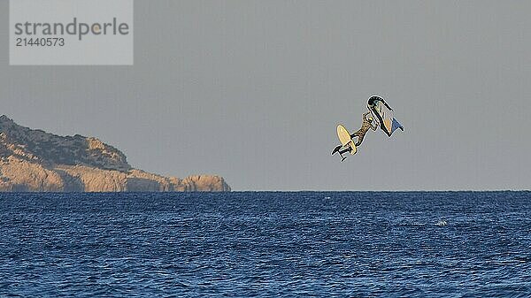 Wingfoiller  surfer jumping high over the sea with cliffs in the background in the evening light  windsurfer  Meltemi windsurfing spot  Devils Bay  Paralia Vatha  Vatha Beach  southeast coast  Karpathos  Dodecanese  Greek Islands  Greece  Europe