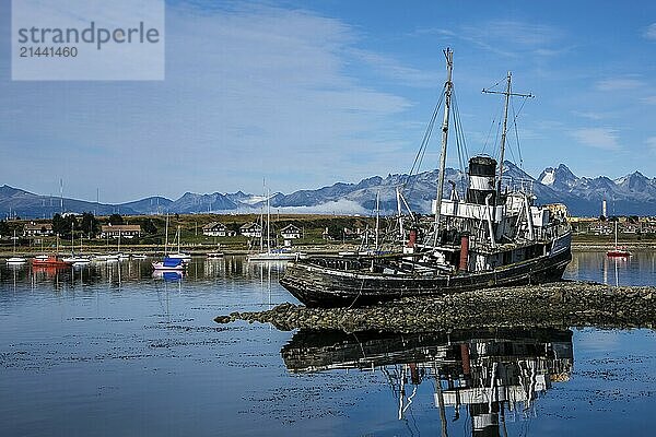 Ushuaia  Tierra del Fuego  Argentina  St Christopher shipwreck in the harbour of Ushuaia on the Beagle Channel  the Beagle Channel is a natural waterway at the southern tip of South America that connects the Atlantic Ocean with the Pacific Ocean. Ushuaia is the southernmost city in the world  the end of the world. Behind mountain range on the island of Navarino in Chile  Dientes de Navarino  South America