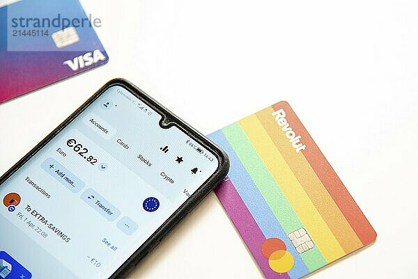 Nicosia  Cyprus  April 3 2022: Smartphone revolut debit card on white background. Mobile phone app cryptocurrency trading online banking  Europe