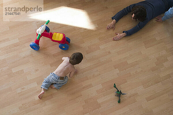 A top view of a small boy crawling toward his mother.