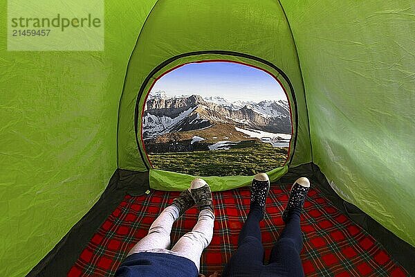 Two kids inside on a camping tent looking at the mountains during the day