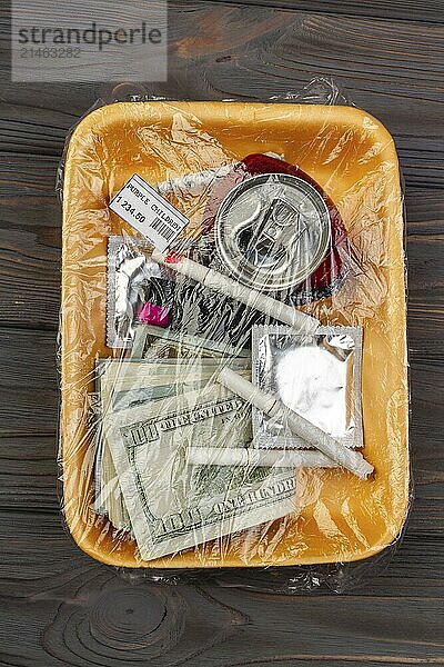 Top view teenage stuff wrapped in plastic. Money with condom and cigarettes