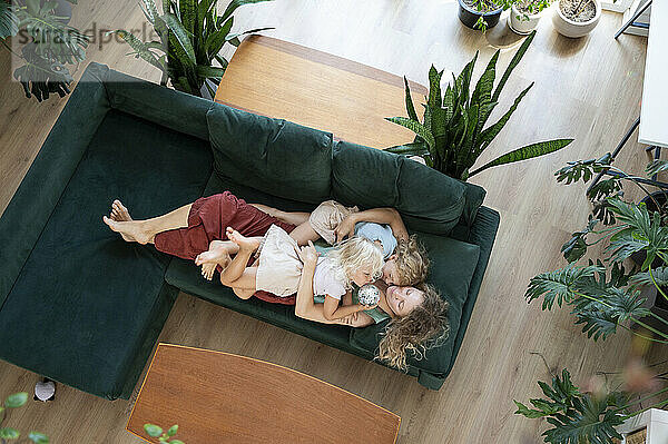 Mature woman relaxing with daughters on sofa at home