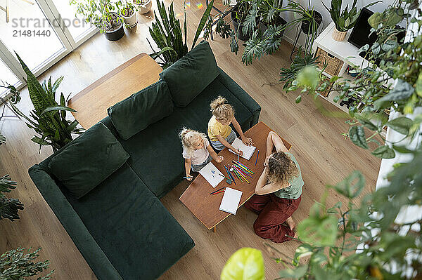 Mature woman with daughters drawing in living room at home