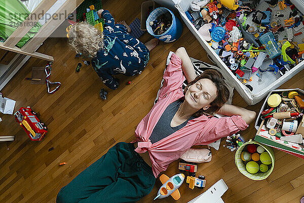 Smiling woman with eyes closed day dreaming amidst toys in bedroom at home