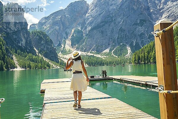 Tourist walking on a wooden pier  enjoying the scenic view of lake braies and the surrounding dolomites mountains in summer