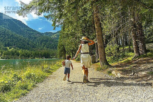 Mother and son enjoying a walk along the scenic shores of lake dobbiaco  surrounded by the stunning beauty of the dolomites in summer