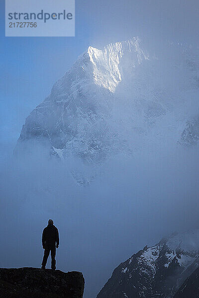 A silhouetted person stands in front of a clearing storm on Taboche peak in the Khumbu region of Nepal.