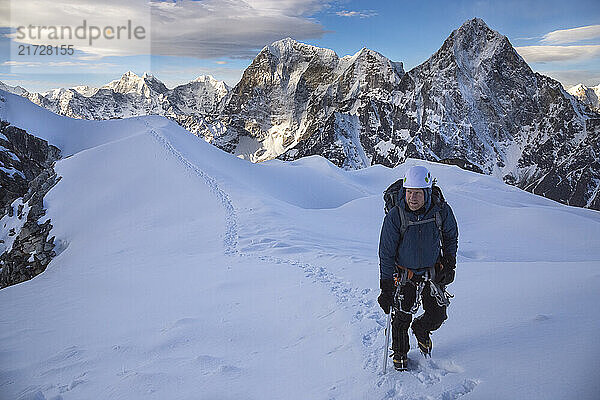 A climber ascends Nepal's Lobuche East at dawn with Cholatse  Taboche  and the Khumbu Valley in the background.