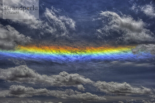 A rainbow strikes contrast between the clouds in a blue sky in Cayonlands  Utah