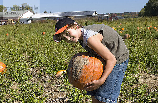 A young boy lifts a heavy pumpkin at Wallkill View Farm Market in New Paltz  New York. Photo by Gabe Palacio