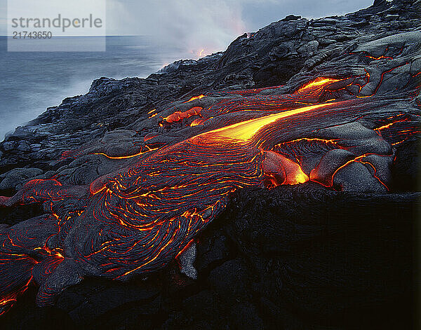 Vibrant lava solidifies on a rocky shore of Hawai?i Volcanoes National Park