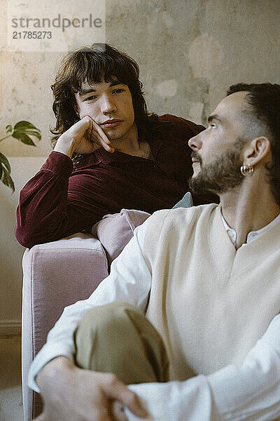 Man looking at boyfriend leaning on elbow at home