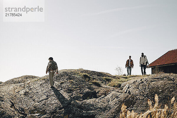 Multiracial male and female walking on hill under clear sky