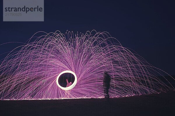 An image of a steel wool firework with shadow of a man