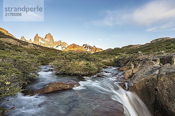 A waterfall with the Fitz Roy mountain illuminated by the morning sun in the Los Glaciares National Park in Argentina