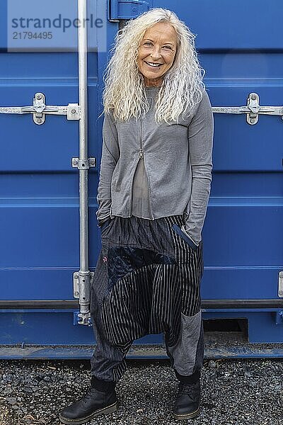 Schöne Frau in den 50ern mit blauem Container im Hintergrund