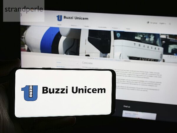 Stuttgart  Germany  06-01-2024: Person holding smartphone with logo of Italian building materials company Buzzi Unicem S.p.A. in front of website. Focus on phone display  Europe