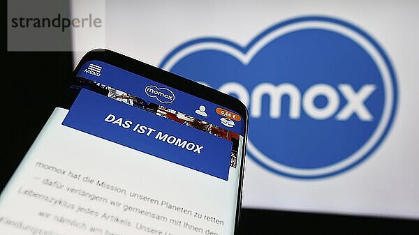 Stuttgart  Germany  03-06-2024: Mobile phone with website of German recommerce company momox SE in front of business logo. Focus on top-left of phone display  Europe