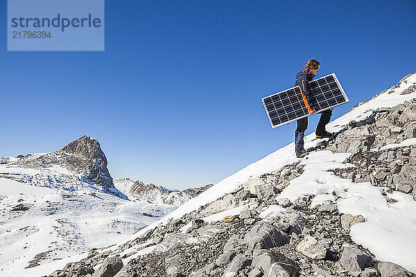 Woman carrying solar panel to instrument station at Plaine Morte Glacier  Bern Canton  Switzerland